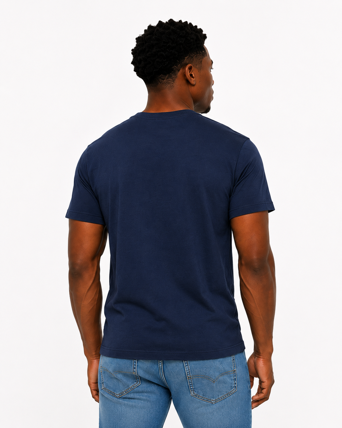 Man wearing a navy blue t-shirt and light blue jeans on a white background
